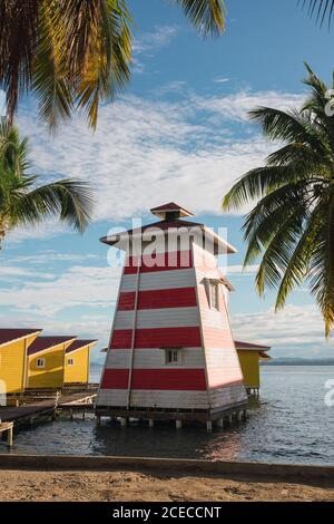 Bord de mer tropical avec petit phare en bois sur la jetée avec des maisons jaunes en rangée, Panama Banque D'Images