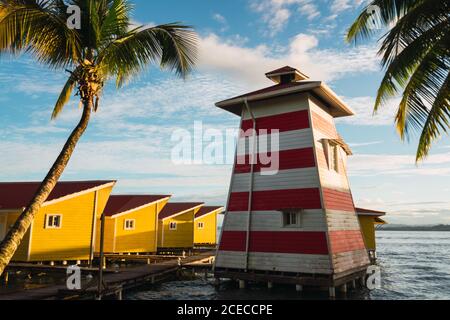 Bord de mer tropical avec petit phare en bois sur la jetée avec des maisons jaunes en rangée, Panama Banque D'Images