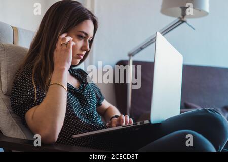 Woman using laptop in armchair Banque D'Images