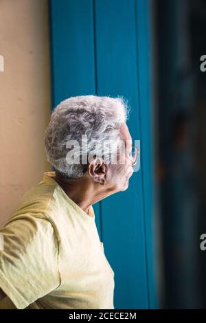 LA HABANA, CUBA - NOVEMBRE, 6 , 2018: Vue de côté des femmes âgées hispanique à cheveux gris dans des lunettes regardant loin près du mur bleu à Cuba Banque D'Images