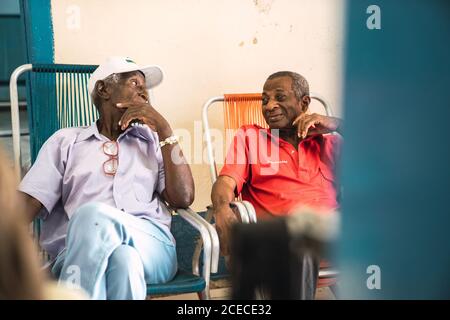 LA HABANA, CUBA - 6 NOVEMBRE 2018: Des hommes afro-américains âgés qui parlent dans la chambre et s'assoyaient sur des chaises pliantes??près du mur rose?à Cuba Banque D'Images