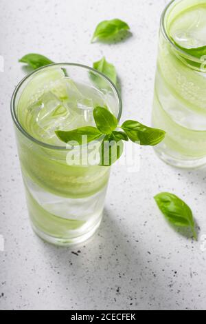 Mise au point sélective, boisson rafraîchissante avec tranches de concombre, dans un grand verre avec des feuilles de basilic vertes Banque D'Images