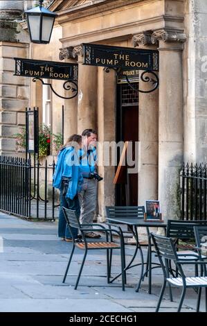 Un couple de visiteurs à l'entrée du roman Bains dans le cimetière de l'abbaye dans la ville romaine de Bath en Grande-Bretagne Banque D'Images