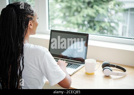 Jeune femme qui profite d'une courte pause après avoir travaillé toute la journée sur un ordinateur portable et en regardant par la fenêtre Banque D'Images