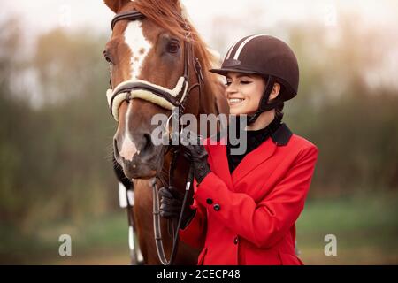 Portrait Jockey femme cavalier avec cheval brun, concept publicitaire école de club équestre Banque D'Images