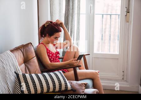 Jeune femme assise dans un fauteuil avec téléphone portable Banque D'Images