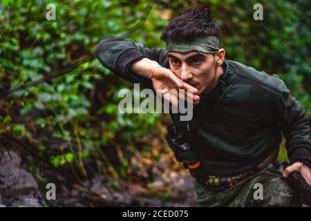 Soldat ou membre révolutionnaire ou chasseur en camouflage près du ruisseau potable de l'eau propre naturelle du cours d'eau Banque D'Images