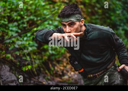 Soldat ou membre révolutionnaire ou chasseur en camouflage près du ruisseau potable de l'eau propre naturelle du cours d'eau Banque D'Images