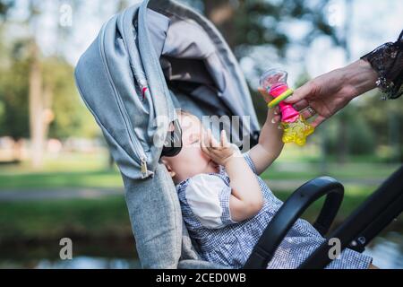 Crop main réconfortant bébé dans le chariot Banque D'Images