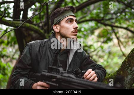 Soldat ou membre révolutionnaire ou chasseur en camouflage sur le arbre observant le canon dans sa main Banque D'Images