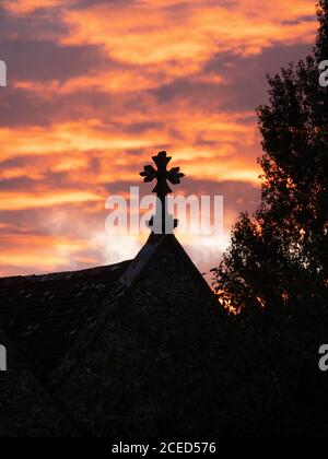 Les croix de l'église de Saint Bartholomée à Shapwick, Dorset, Royaume-Uni, ont silhoueté contre le ciel radieux du coucher du soleil. Banque D'Images