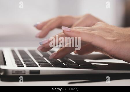 Les femmes tapissent du texte sur un ordinateur portable, recherchent des informations sur les réseaux sociaux, les femmes tapissent du texte sur netbook pour discuter. Concept travail à distance, technologie. Photo de haute qualité Banque D'Images