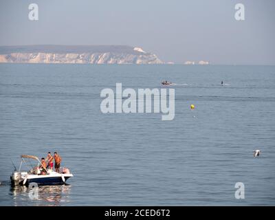 Bateau à vitesse avec vacanciers au large de la côte d'Avon plage à Mudeford, Christchurch, Dorset avec l'île de Wight et les aiguilles phare derrière. Banque D'Images