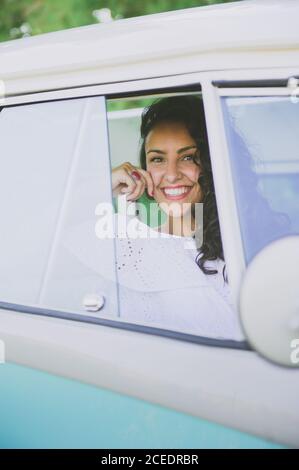 Belle jeune femme souriant et regardant l'appareil photo tout en étant assis à l'intérieur belle voiture dans la nature Banque D'Images