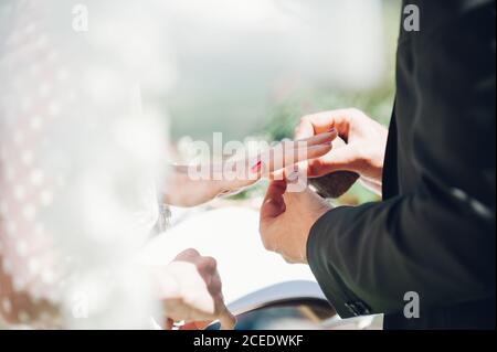 Jeune homme et femme échangeant des anneaux de mariage dans le jardin Banque D'Images