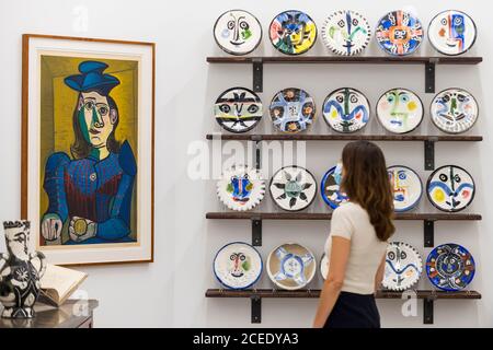 Londres, Royaume-Uni. 1er septembre 2020. Un membre du personnel pose avec (de L à R) 'Femme assise (Dora Maar) [Femme assise (Dora Maar)]', 1955, et 'l'ensemble complet de 20 'plaques de visite', 1963, tous par Pablo Picasso. Avant-première de l'atelier Picasso, une nouvelle exposition recréant le studio de Pablo Picasso à Cannes avec ses dessins, ses gravures, ses céramiques et ses meubles. Le spectacle est à la galerie Bastian à Mayfair du 3 septembre au 31 octobre 2020. Les visiteurs devront porter un masque facial et pratiquer la distanciation sociale. Credit: Stephen Chung / Alamy Live News Banque D'Images