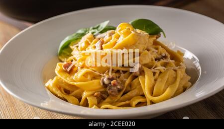 Pâtes italiennes tagliatelle carbonara avec galette de pancetta au jaune d'œuf au parmesan et feuilles de basilic Banque D'Images