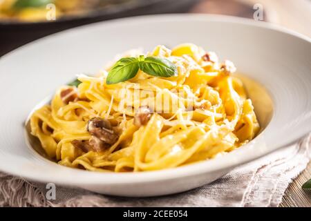 Pâtes italiennes tagliatelle carbonara avec galette de pancetta au jaune d'œuf au parmesan et feuilles de basilic Banque D'Images