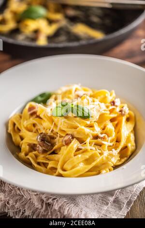 Pâtes italiennes tagliatelle carbonara avec galette de pancetta au jaune d'œuf au parmesan et feuilles de basilic Banque D'Images