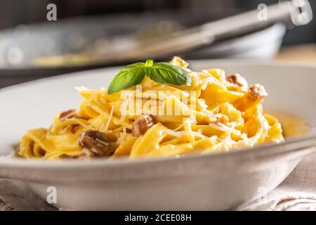 Pâtes italiennes tagliatelle carbonara avec galette de pancetta au jaune d'œuf au parmesan et feuilles de basilic Banque D'Images