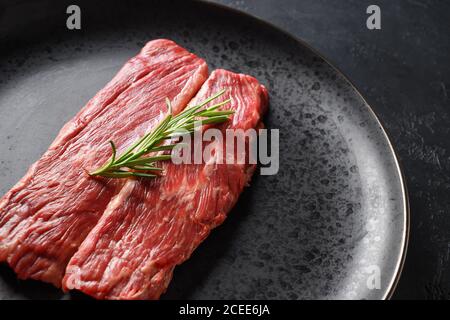 Steak de ribeye marbré cru dans une assiette noire. Copier l'espace Banque D'Images