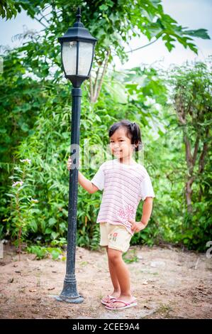 Une jeune fille thaïlandaise joueuse joue dans le jardin de sa maison familiale. Banque D'Images