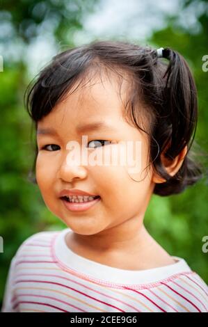 Une jeune fille thaïlandaise joueuse joue dans le jardin de sa maison familiale. Banque D'Images