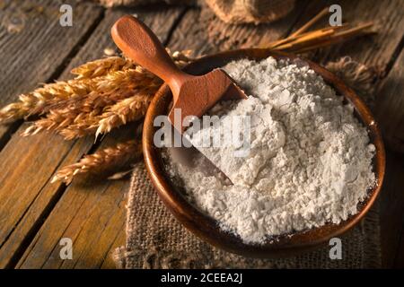 Farine naturelle, biologique, complète dans un bol en bois avec la cuillère. Épis de blé sur un fond en bois ancien. Composition de style vintage sur le Bo rustique Banque D'Images