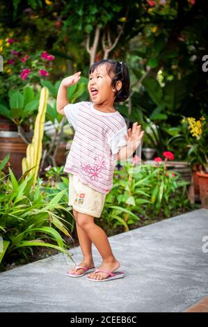 Une jeune fille thaïlandaise joueuse joue dans le jardin de sa maison familiale. Banque D'Images