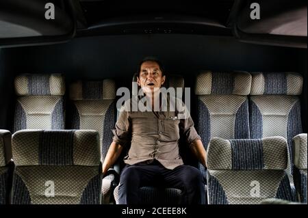 Homme senior assis sur un siège confortable dans le bus avec expression de plaisir. Banque D'Images
