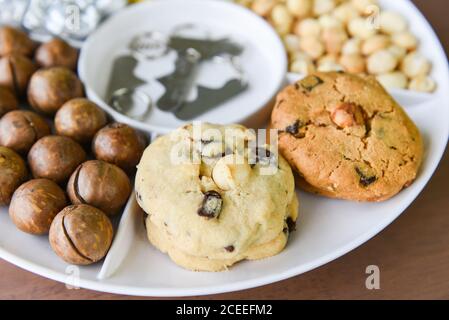 Jeu d'emballages de noix de macadamia sur plateau plat naturel haut protéines / biscuits chocolat aux noix de macadamia Banque D'Images