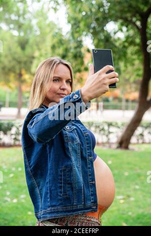 Femme enceinte attrayante utilisant un téléphone portable Banque D'Images