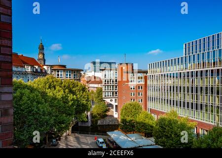 Vue sur la ville depuis la fenêtre de la vieille maison en briques. Paysage urbain du centre-ville de Hambourg avec bâtiment d'entreprise moderne et tour d'horloge ancienne sur la ligne d'horizon Banque D'Images