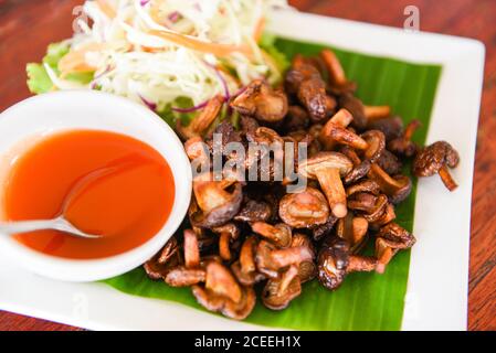 Délicieux champignons frits dans une assiette sur une table en bois, vue du dessus / champignons shiitake cuits frits avec sauce tomate et légumes Banque D'Images