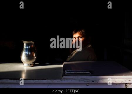 INDE - 3 octobre 2011: Homme en costume assis derrière la table avec pichet et regardant la caméra. Banque D'Images