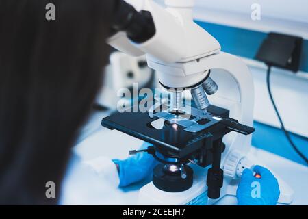 Jeune femme utilisant un microscope en laboratoire Banque D'Images