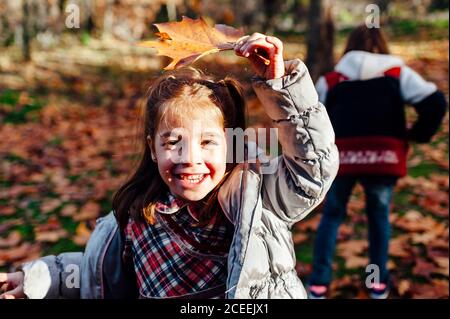 Petite fille tenant une feuille sèche tout en souriant à la caméra dans la campagne Banque D'Images