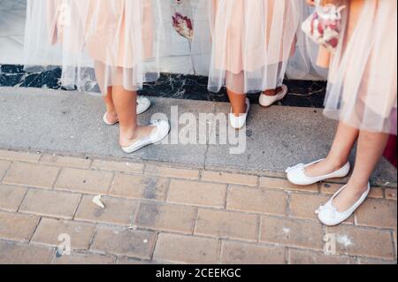 Récoltez des demoiselles d'honneur non reconnaissables dans les mêmes vêtements que ceux qui se trouvent sur le trottoir. Banque D'Images