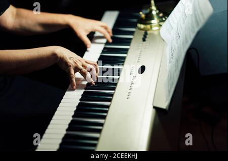 Vue latérale de crop Hands de musicien assis et jouant du piano électrique. Banque D'Images