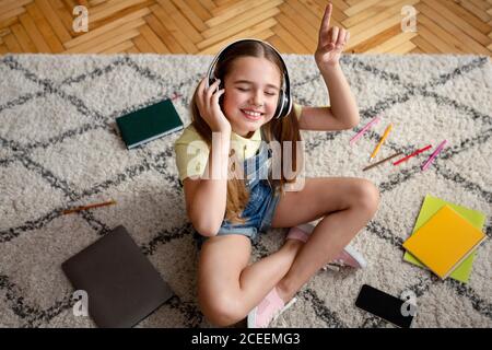 Fille écoutant de la musique assis sur le tapis Banque D'Images