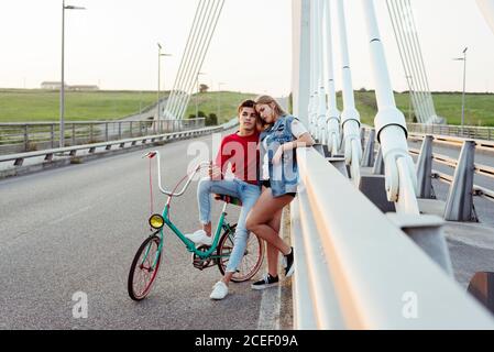 Jeune couple debout sur le pont avec vélo d'époque Banque D'Images