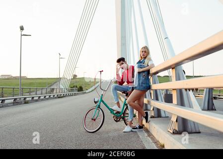 Jeune couple debout sur le pont avec vélo d'époque Banque D'Images