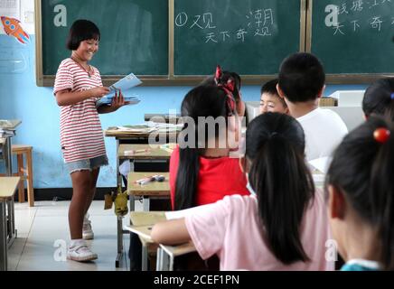 (200901) -- HEFEI, 1er septembre 2020 (Xinhua) -- lu Suzi (L) distribue des manuels scolaires dans la salle de classe de l'école centrale de Changlinhe, dans le comté de Feidong, Hefei, province d'Anhui, en Chine orientale, le 31 août 2020. Lu Suzi, né en 2011, est un élève de l'école primaire dans le comté de Feidong. En juillet, sous la menace de graves inondations, elle et sa famille ont été évacuées vers un lieu de réinstallation sûr, où elles ont reçu des soins et une attention méticuleuses de la part de bénévoles. Au fur et à mesure que les eaux de crue s'estompage, la vie de lu Suzi a commencé à revenir à la normale. L'école centrale de la zone scolaire de Changlinhe a officiellement ouvert ses portes lundi A. Banque D'Images