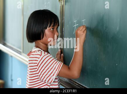 (200901) -- HEFEI, 1er septembre 2020 (Xinhua) -- lu Suzi écrit sur le tableau noir de l'école centrale de Changlinhe, dans le comté de Feidong, Hefei, dans la province d'Anhui, en Chine orientale, le 31 août 2020. Lu Suzi, né en 2011, est un élève de l'école primaire dans le comté de Feidong. En juillet, sous la menace de graves inondations, elle et sa famille ont été évacuées vers un lieu de réinstallation sûr, où elles ont reçu des soins et une attention méticuleuses de la part de bénévoles. Au fur et à mesure que les eaux de crue s'estompage, la vie de lu Suzi a commencé à revenir à la normale. L'école centrale de la zone scolaire de Changlinhe a officiellement ouvert lundi et lu, qui a bec Banque D'Images