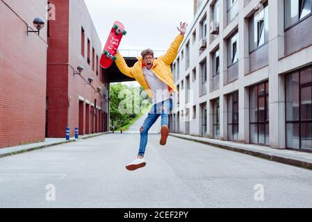 Hurlant, un jeune adolescent enthousiaste sautant avec un skateboard sur le rue Banque D'Images