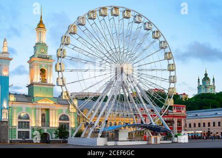 Grande roue sur la place Kontraktova, zone touristique, crépuscule, architecture illuminée au crépuscule, Kiev, Ukraine Banque D'Images