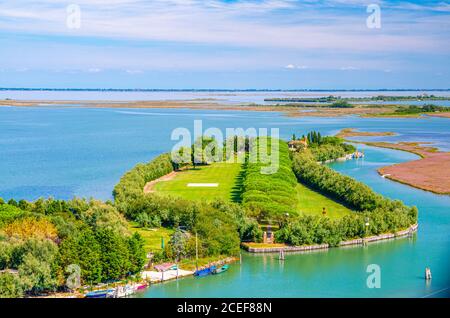 Vue aérienne du marais des îles Torcello, du canal d'eau et de la ruelle et des buissons verdoyantes. Vue panoramique sur la lagune vénitienne depuis le clocher. Vénétie, Nord de l'Italie. Fond bleu ciel nuageux. Banque D'Images