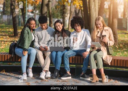 Adolescents toxicomanes utilisant des gadgets tout en passant du temps dans le parc Banque D'Images