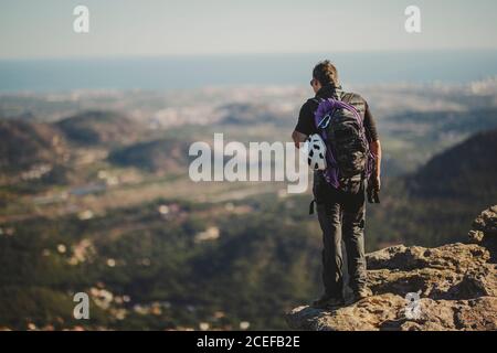 Vue arrière de l'homme avec sac à dos et équipement d'escalade debout Au sommet de la montagne Garbi et vue sur la nature majestueuse Le jour ensoleillé à Djibouti Banque D'Images