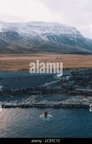 Vue de la femme nageant dans l'eau bleue du réservoir naturel avec les montagnes sur fond Banque D'Images